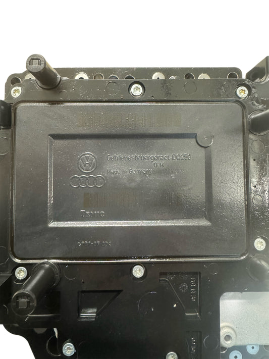 02E927770AE DSG DQ250 mechatronics top label view showing Volkswagen Group logo, Audi rings logo, Getriebe label DQ250, Made in Germany, TEMIC manufacturer marking, and hydraulic connector ports